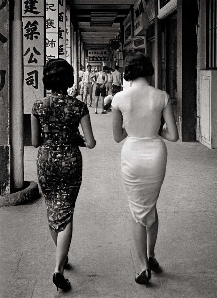 Women in tightly fitted qipaos walking down the street in Hong Kong in the 1950s; source unknown