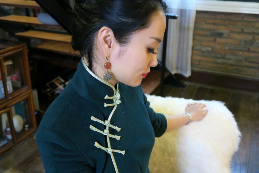 Wearing forest green cashmere qipao with apple green edging and pankou