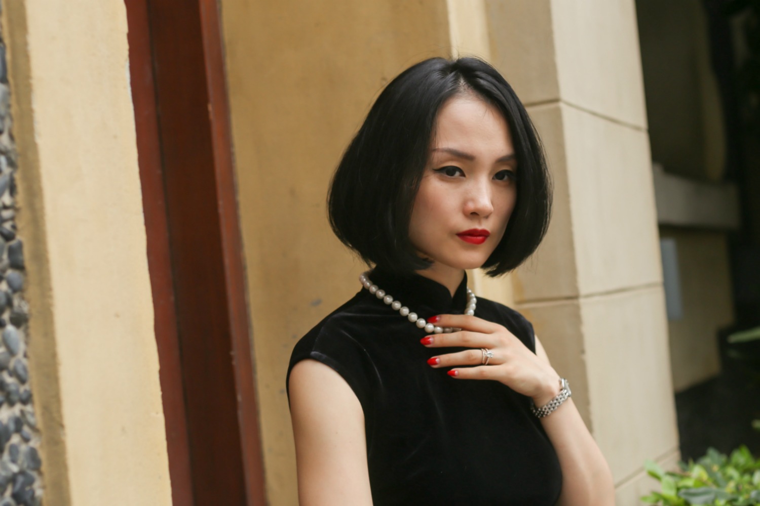 Miranda wearing black sleeveless velvet qipao and pearls